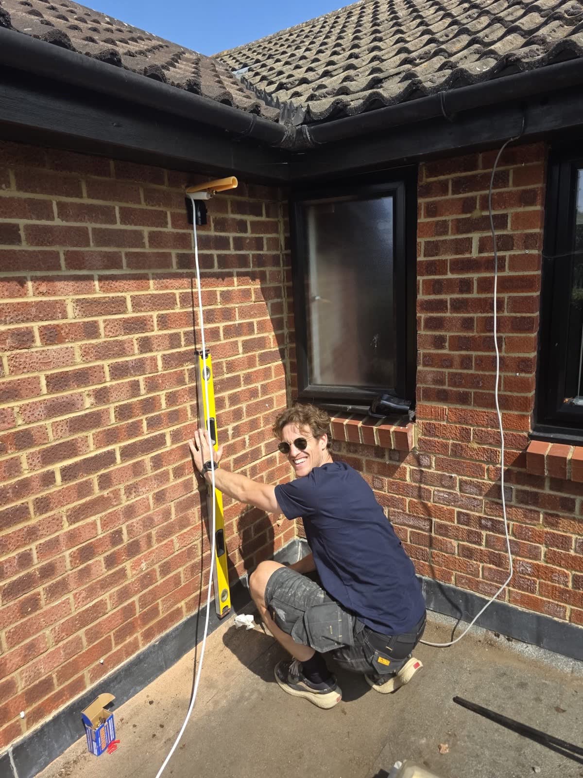Engineer using a spirit level to mark out an air conditioning pipework route on a brick wall